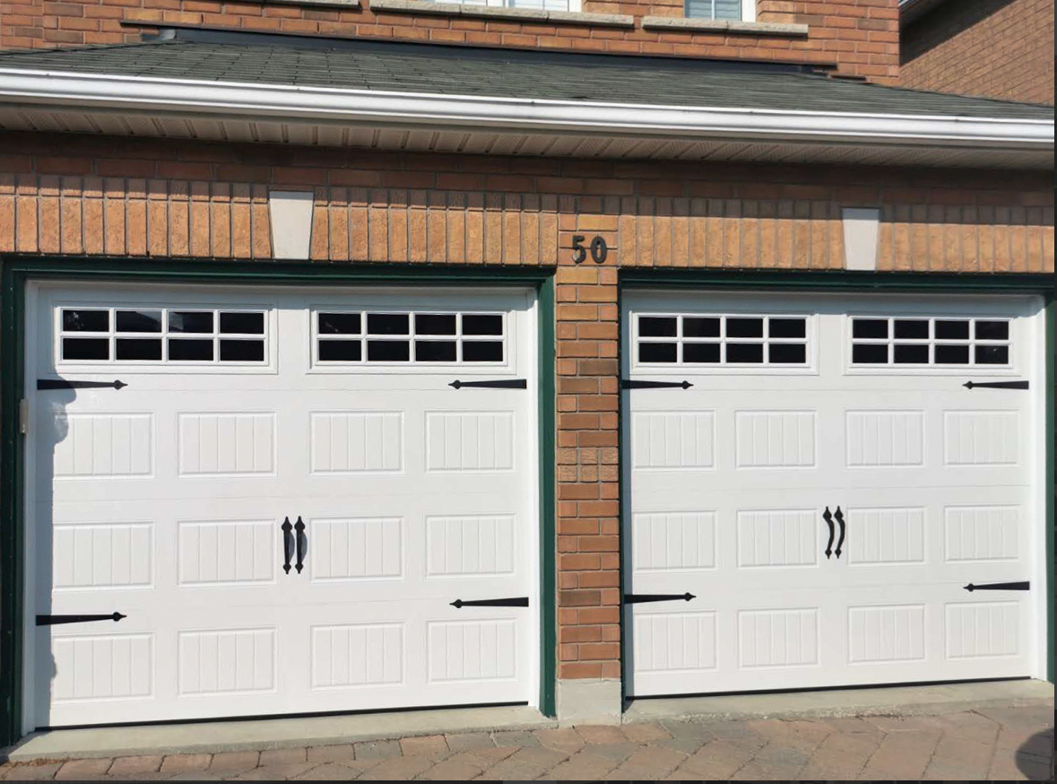 White carriage-house style garage door with decorative black hardware