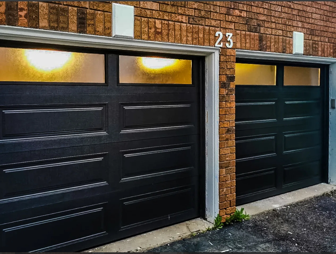 Dark insulated steel raised-panel garage door on a brick home